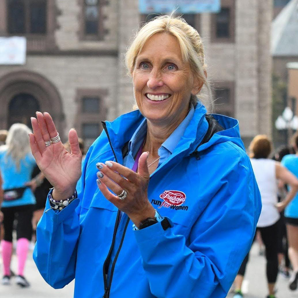 Kristen Hislop in a blue jacket smiling and clapping hands