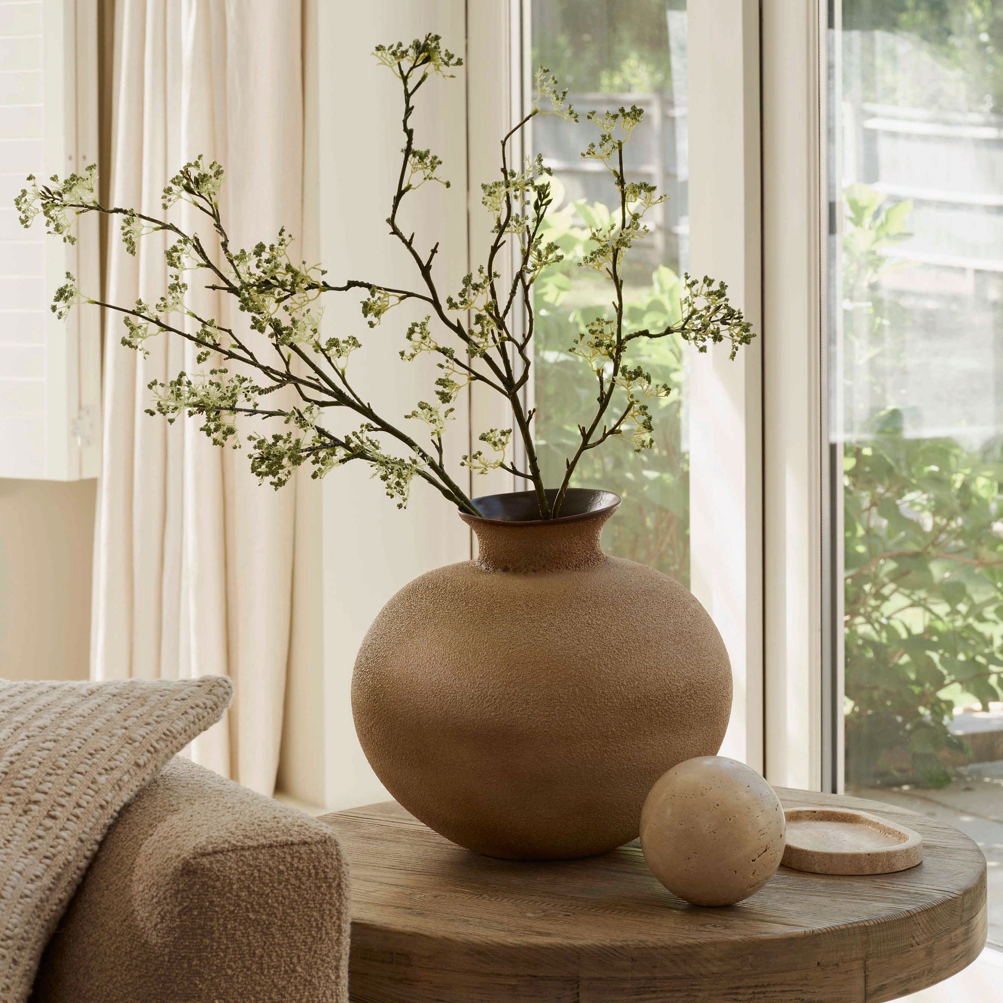 Round wooden table with round vase and blossom branch coming out the top