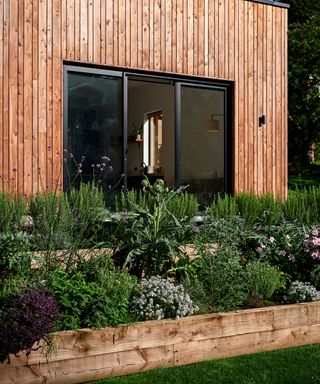 Raised garden beds made of timber gravel board in front of a timber clad self build home
