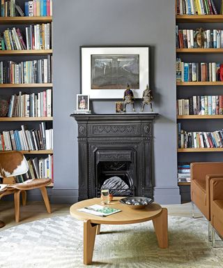 living room with blue wall fireplace book shelf and brown sofa with chair