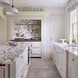 White kitchen with island, marble worksurfaces and large AGA range
