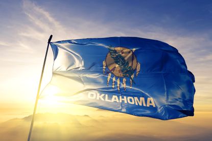 pictue of Oklahoma state flag on pole against golden sky