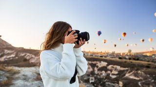 Fotograf står på en höjd med varmluftsballonger i bakgrunden