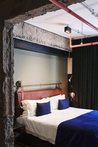 hotel room at Gorgeous George, blue bedding and cement walls