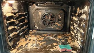 open oven with the interior covered in a baking soda paste during cleaning