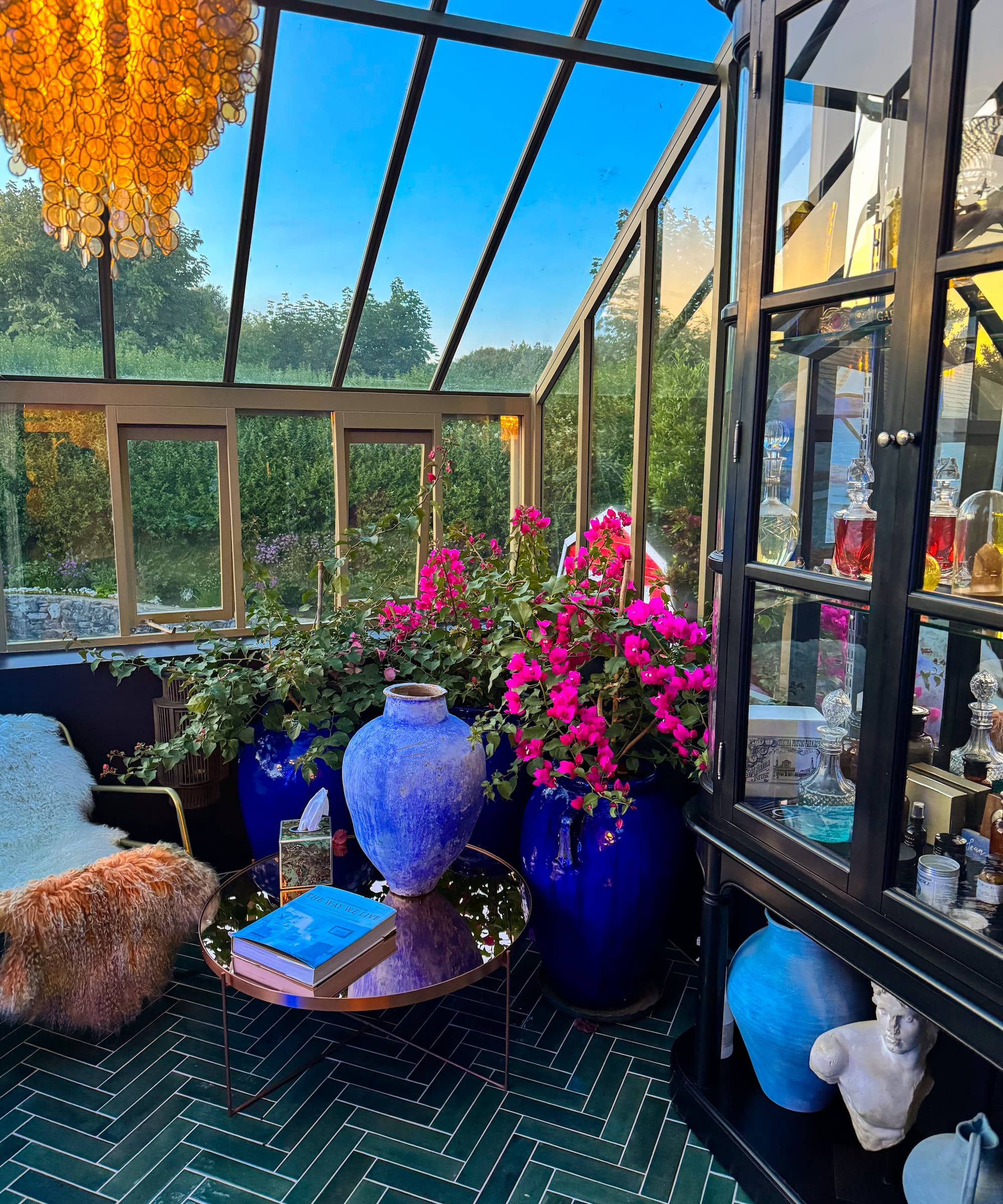A greenhouse with green tiled flooring and plants in the corner and a side cabinet