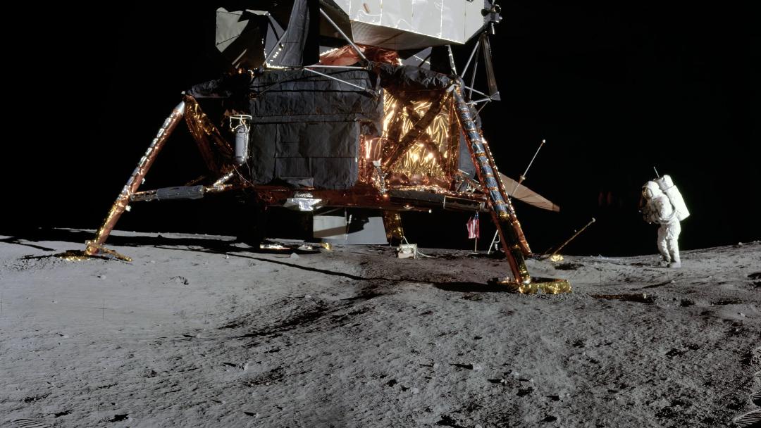 a gold-foil-covered conical spacecraft sits on a grey dusty surface