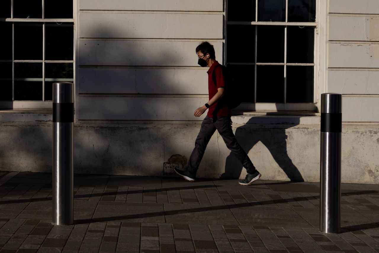 A man walking in front of a sun-drenched wall