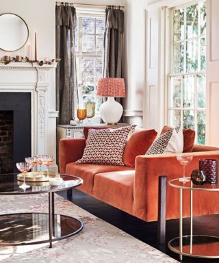living room with orange velvet sofa, glass coffee table and fireplace