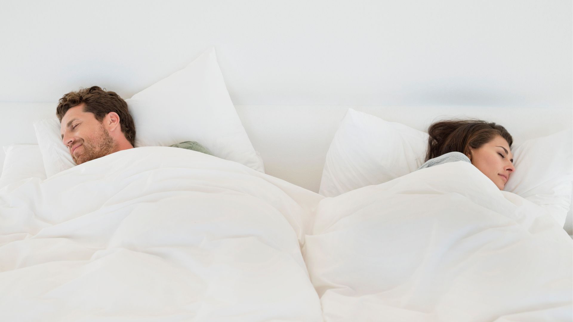 A couple sleeping happily at opposite sides of the bed