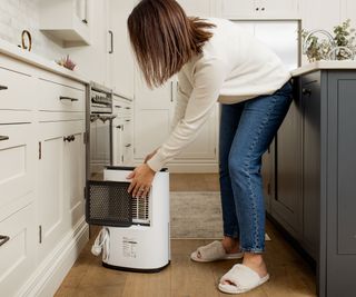 Women removing air filter on Meaco dehumidifier in kitchen