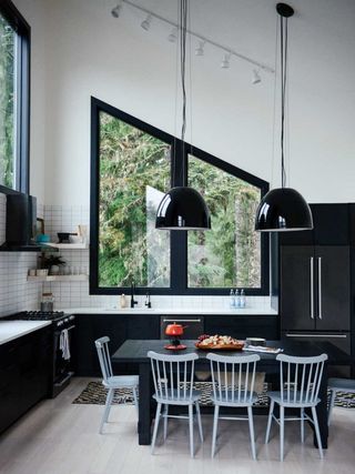 Kitchen table in a black and white kitchen with large architectural windows.