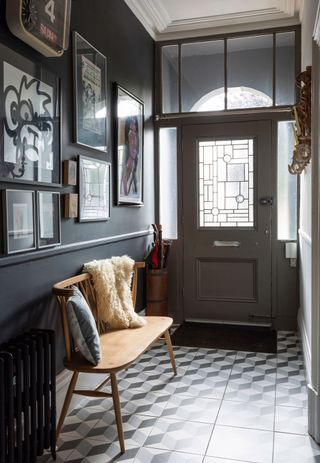 a dark grey hallway with artwork and a wooden bench on it; Matt and Emma Rawlinson transformed a run-down property full of bedsits in Cheltenham into a vibrant family home