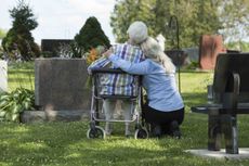 older people hugging at a gravesite
