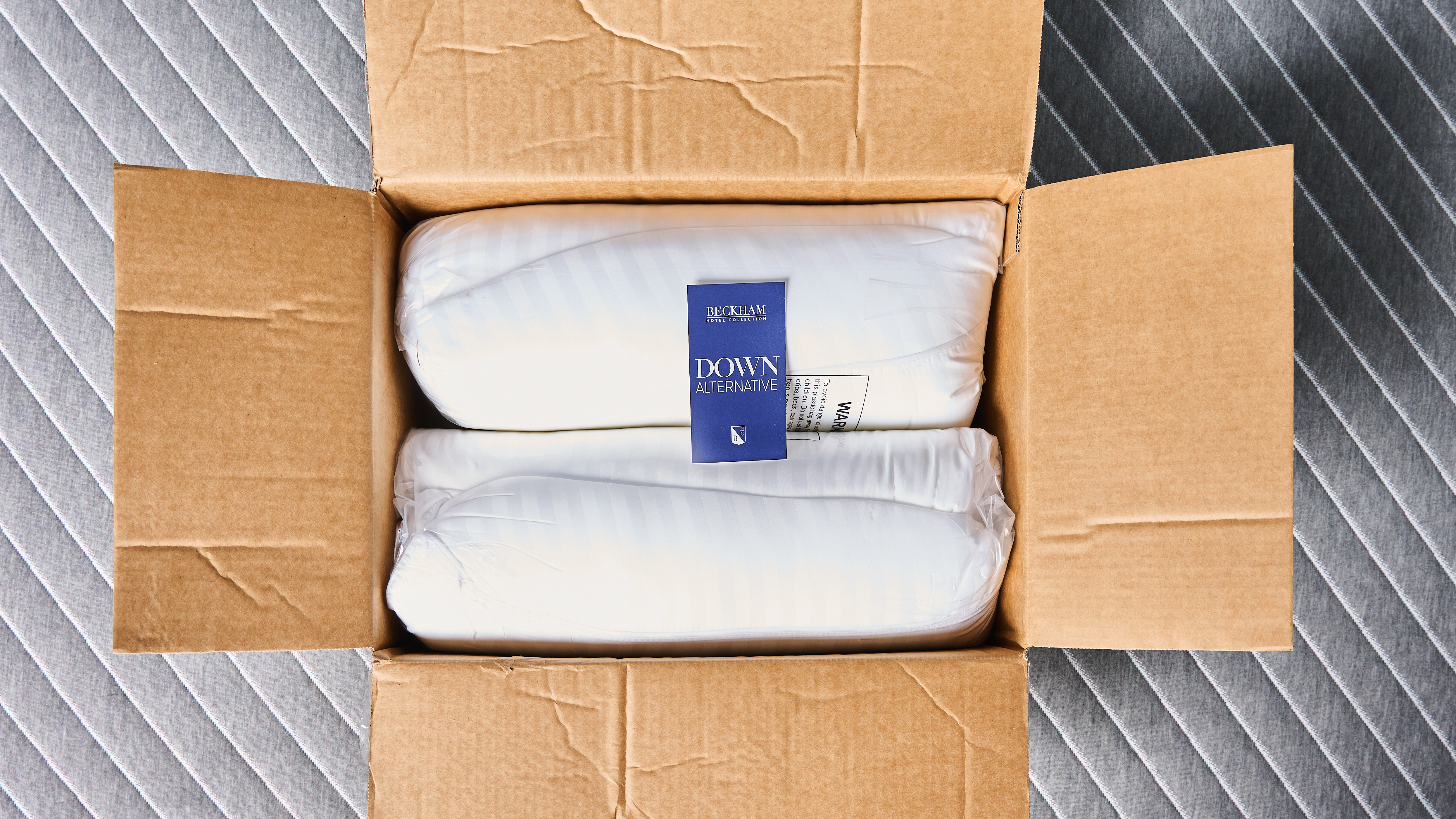 Beckham Hotel Collection Down-Alternative Pillows rolled up inside the box