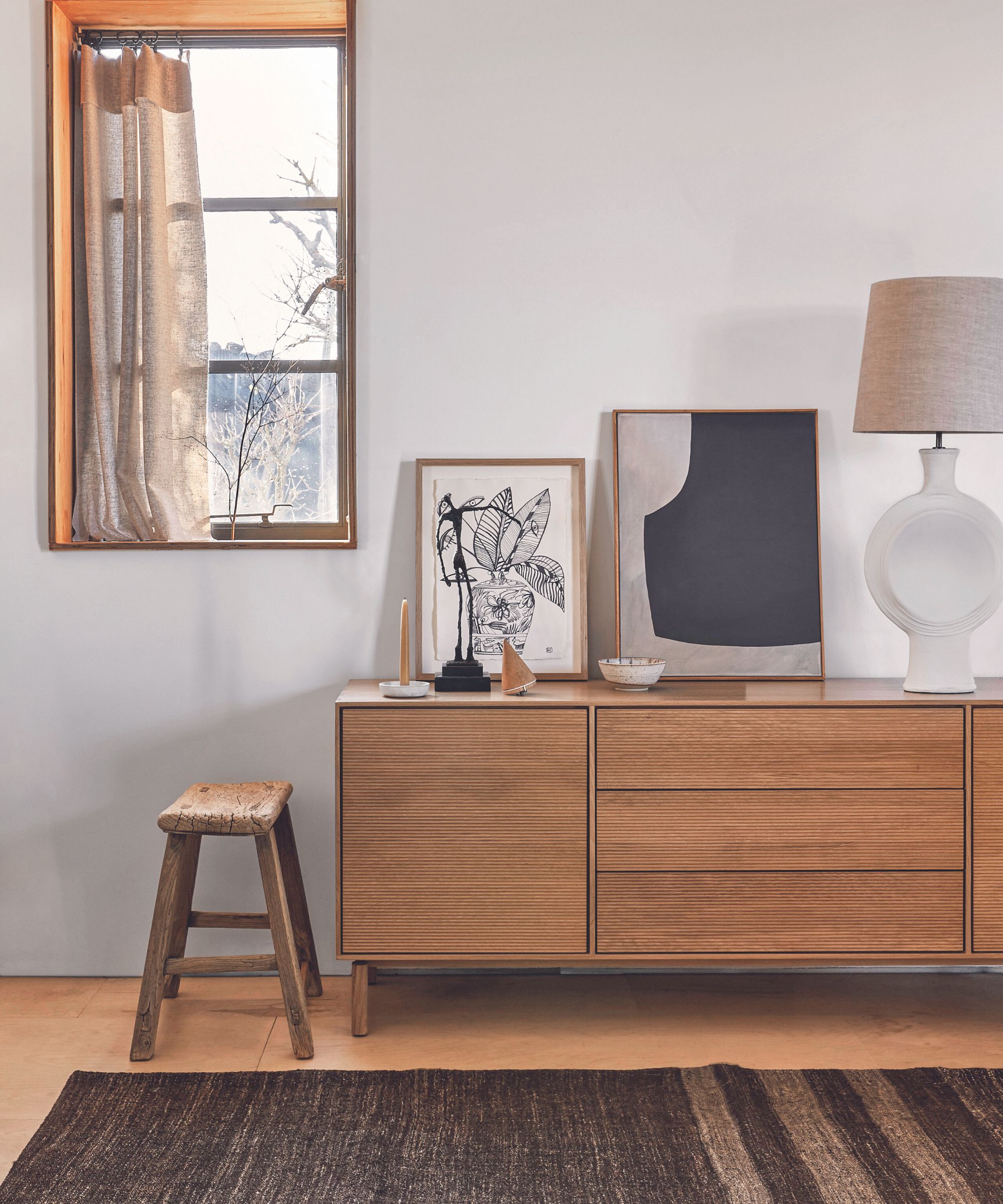 Wooden sideboard on a wooden floor, black rug and grey walls.