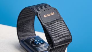 the amazfit helio strap fitness tracker with a screenless design, showing the gray strap worn around the wrist and the charger