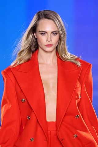 Cara Delevingne walks the runway during "Le Défilé L'Oréal Paris – Walk Your Worth" Womenswear Spring-Summer 2025 show as part of Paris Fashion Week on September 23, 2024 in Paris, France wearing a red topcoat and underwear