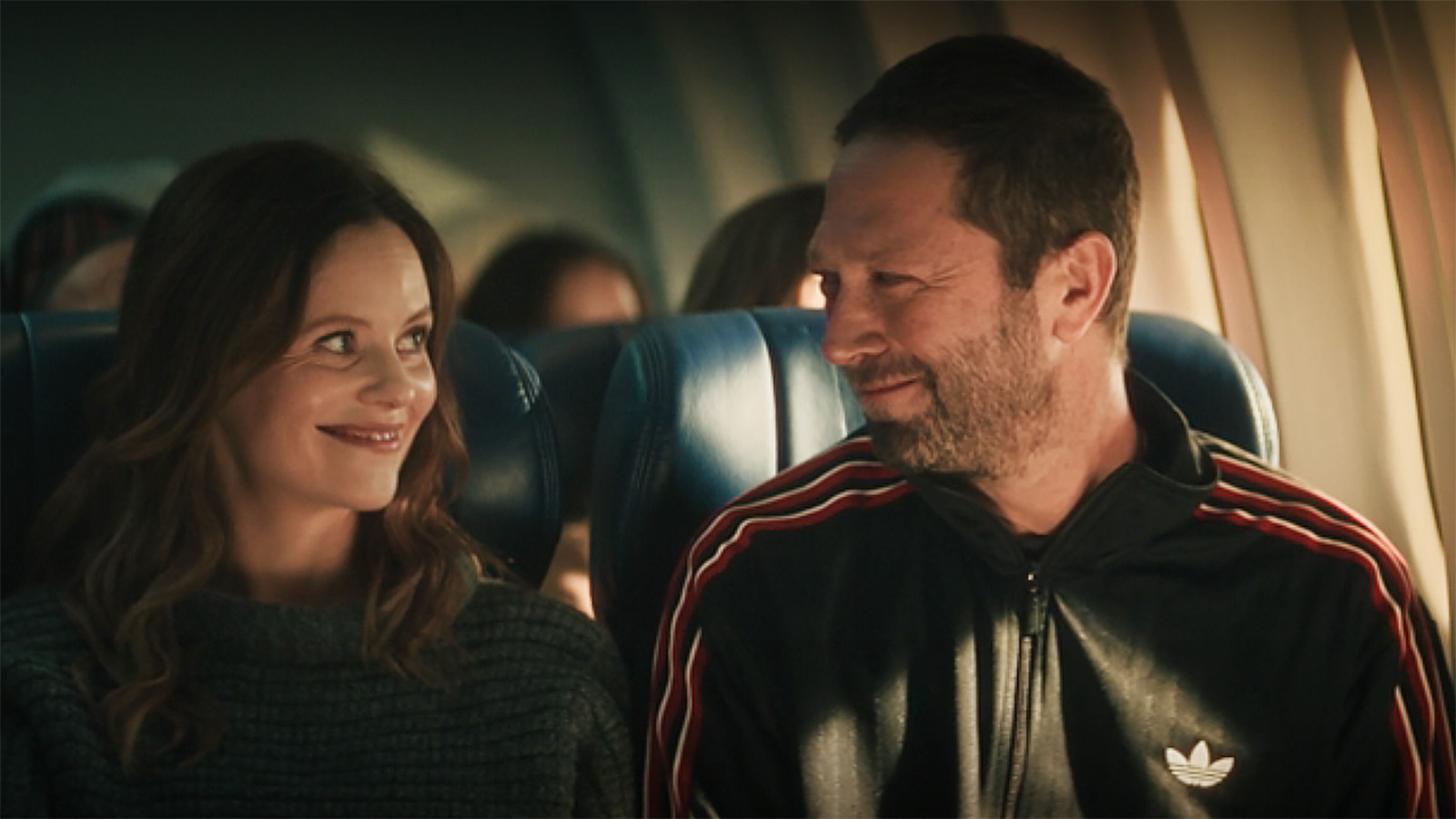 Jessica and Richie smiling at one another on a plane in The Bear season 5