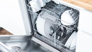 An open dishwasher showing clean crockery and cutlery inside