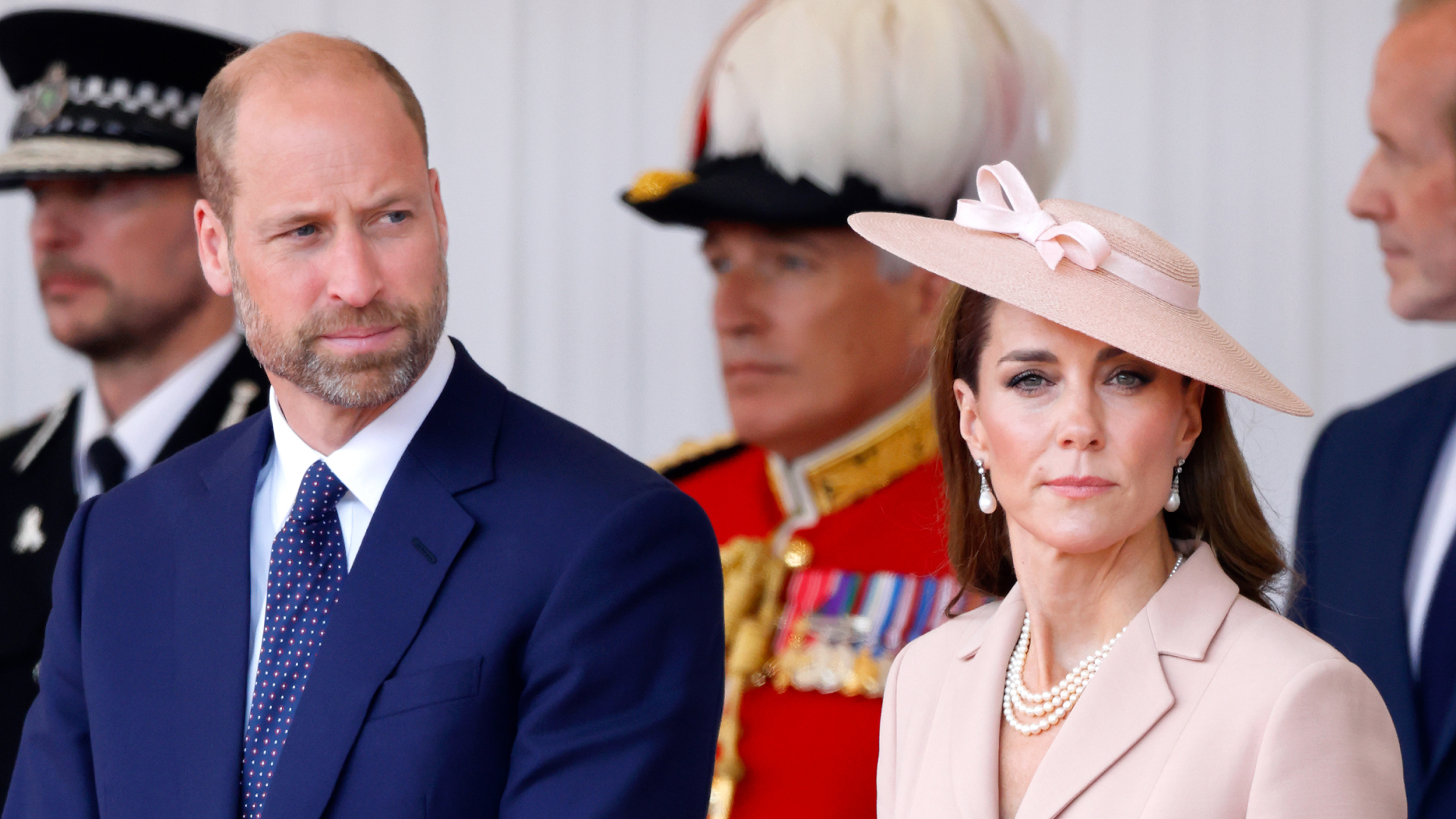 Prince William wears a suit and Kate Middleton wears a pale pink suit and matching hat