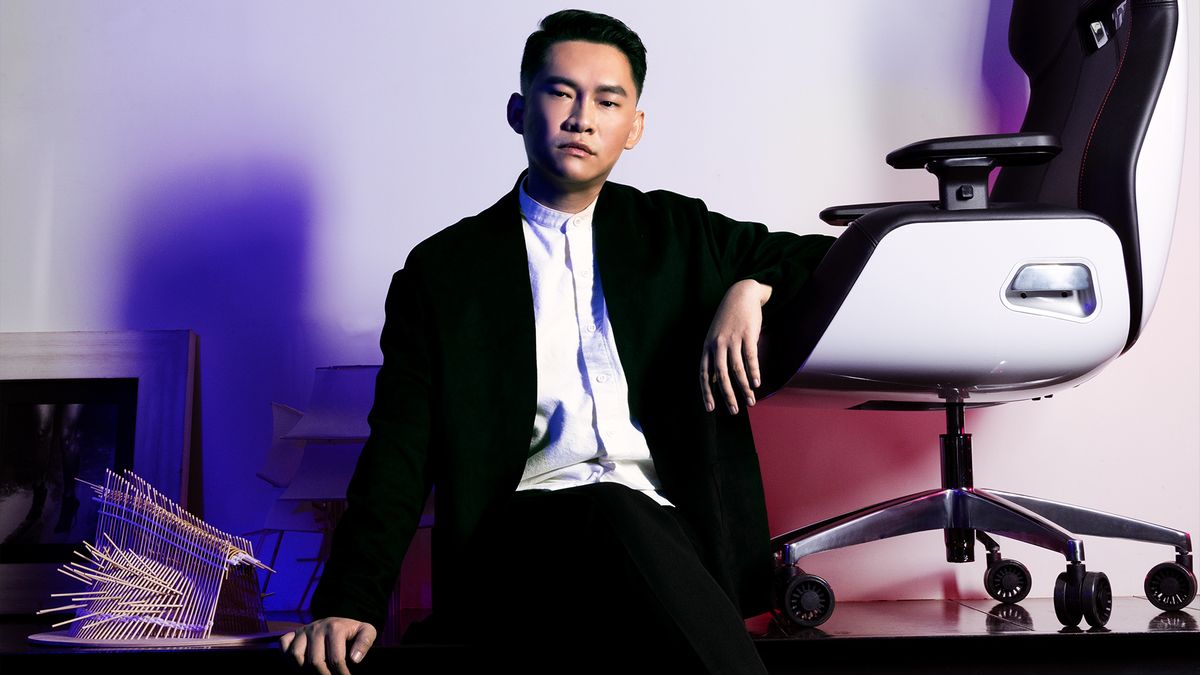 A man looking very serious sitting beside a scifi chair.