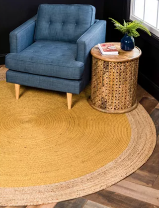 high angle view of a yellow jute round rug with an armchair and side table on top