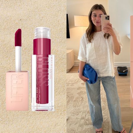 girl in jean and a white top with a blue bag taking a mirror selfie next to two pink lipsticks