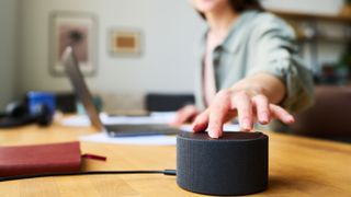 Woman pressing a button on a smart speaker