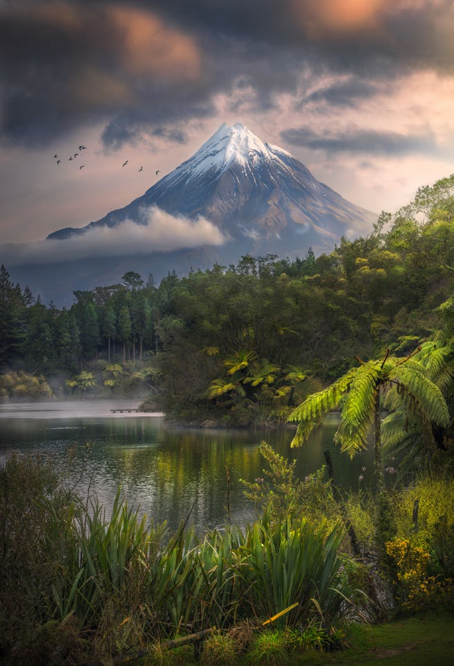 A snowcapped mountain with tropical lake foreground