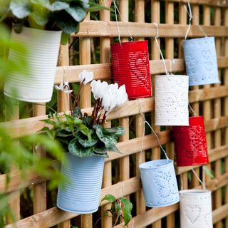 Wooden trellis will tin cans upcycled into tealight and plant holders