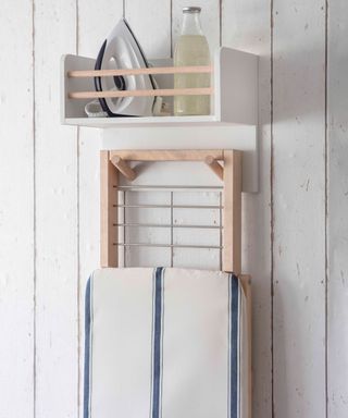 a wall mounted ironing shelf and iron hanger on a distressed wallfrom garden trading