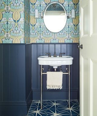 shower room with dark blue paneling, blue patterned flooring, blue, white and green patterned wallpaper and white washstand