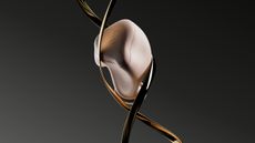 A BREGGZ earbud in a metal cage, suspended, on dark background