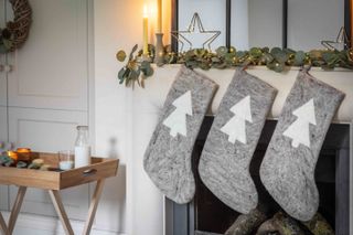 A living room with three grey christmas stockings on a fireplace