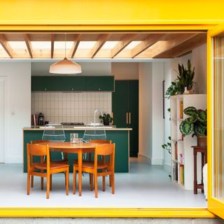 yellow framed bifold doors fully opened to reveal an open plan kitchen diner