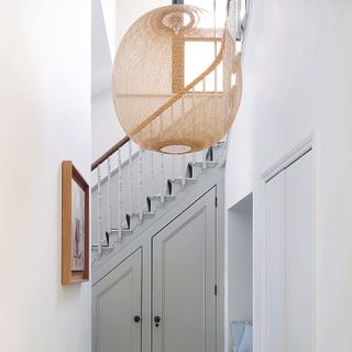 hallway with grey under stairs cupboard and rattan pendant light.