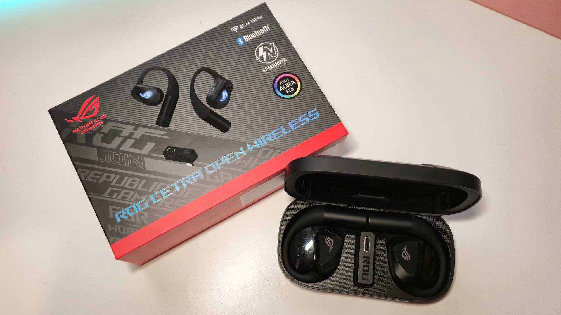 Photo of the Asus ROG Cetra Open Wireless Gaming Earbuds inside their case next to the official box packaging.