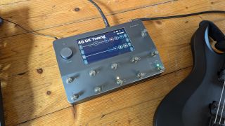 A Neural DSP Quad Cortex on a wooden floor with an electric guitar