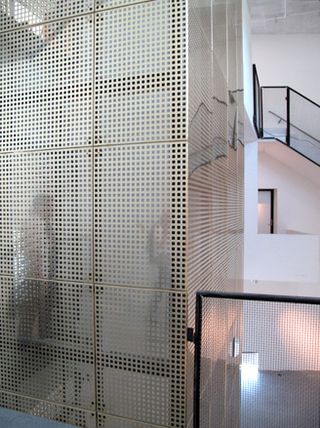 Hearning Museum of Contemporary Art by Steven Holl, Denmark. The inside of a building with square patterned see through walls and staircases with glass railings.