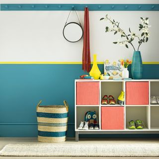 Three-colored hallway wall with a sideboard storage unit, a hanging rack and colorful décor