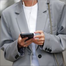 Diane Batoukina wears a white t-shirt, a pale gray blazer jacket, matching pale gray large suit pants, a black and gray FF monogram print pattern denim / velvet handbag from Fendi, during a street style fashion photo session, on April 07, 2023 in Paris, France. (Photo by Edward Berthelot/Getty Images)