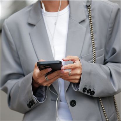 Diane Batoukina wears a white t-shirt, a pale gray blazer jacket, matching pale gray large suit pants, a black and gray FF monogram print pattern denim / velvet handbag from Fendi, during a street style fashion photo session, on April 07, 2023 in Paris, France. (Photo by Edward Berthelot/Getty Images)