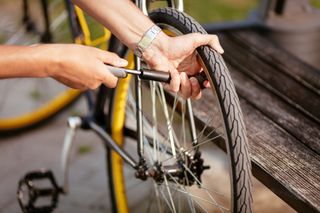 How to fix a puncture and mend an inner tube image shows someone pumping up a rear tyre with a mini pump