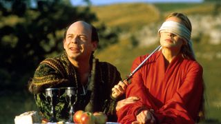 Wallace Shawn, as Vizzini, casually holds a knife to the throat of Robin Wright (as Buttercup/The Princess Bride) throat, as they sit at a table in The Princess Bride