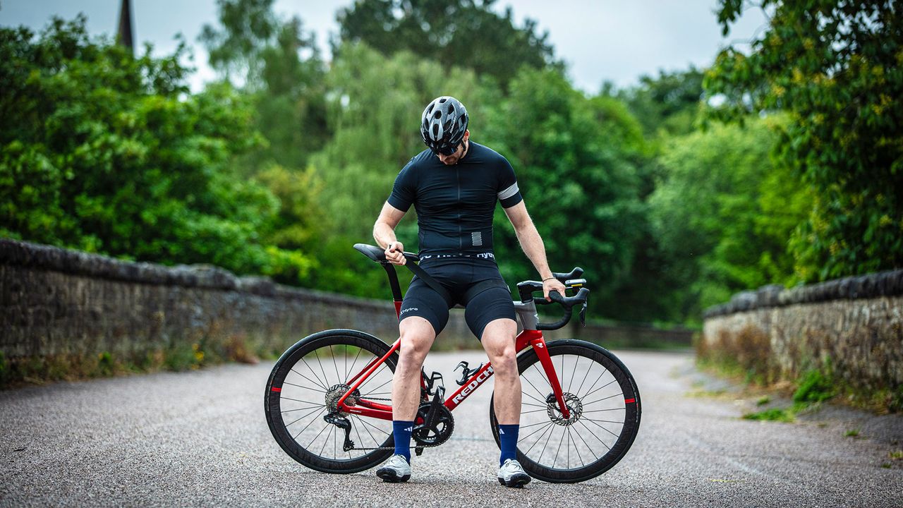 Joe Truman wearing Hytro shorts, sitting on top tube of bike