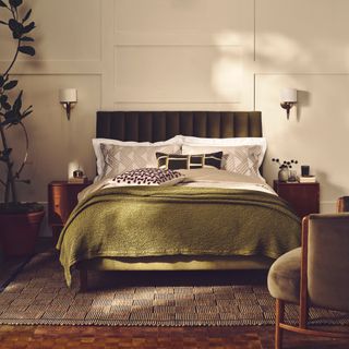 Cosy bedroom with green velvet bed dressing in neutrals with a green waffle throw