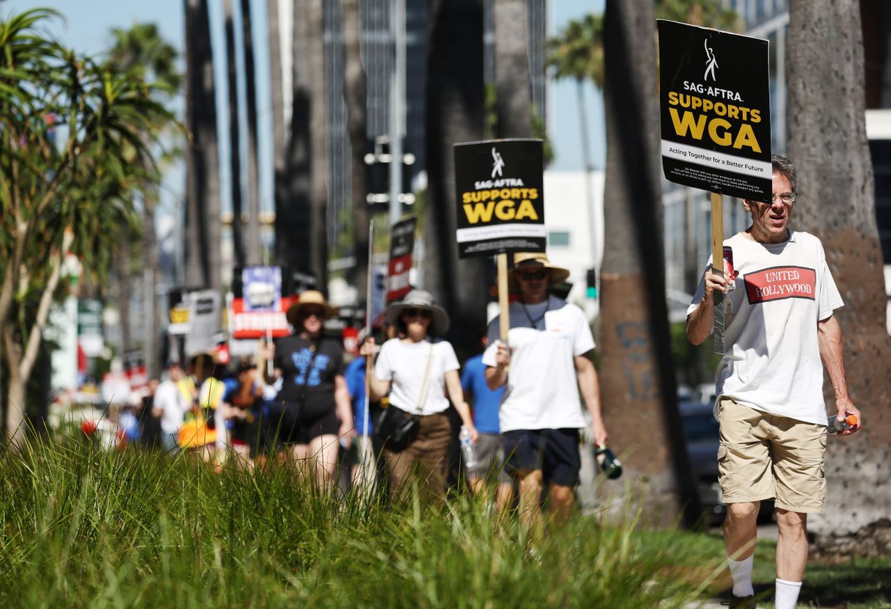 A picket line with people holding protest signs supporting Hollywood actors and writers