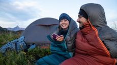 best lightweight sleeping bags: Two campers having hot drinks on their Decathlon Forclaz Trek MT900 sleeping bags