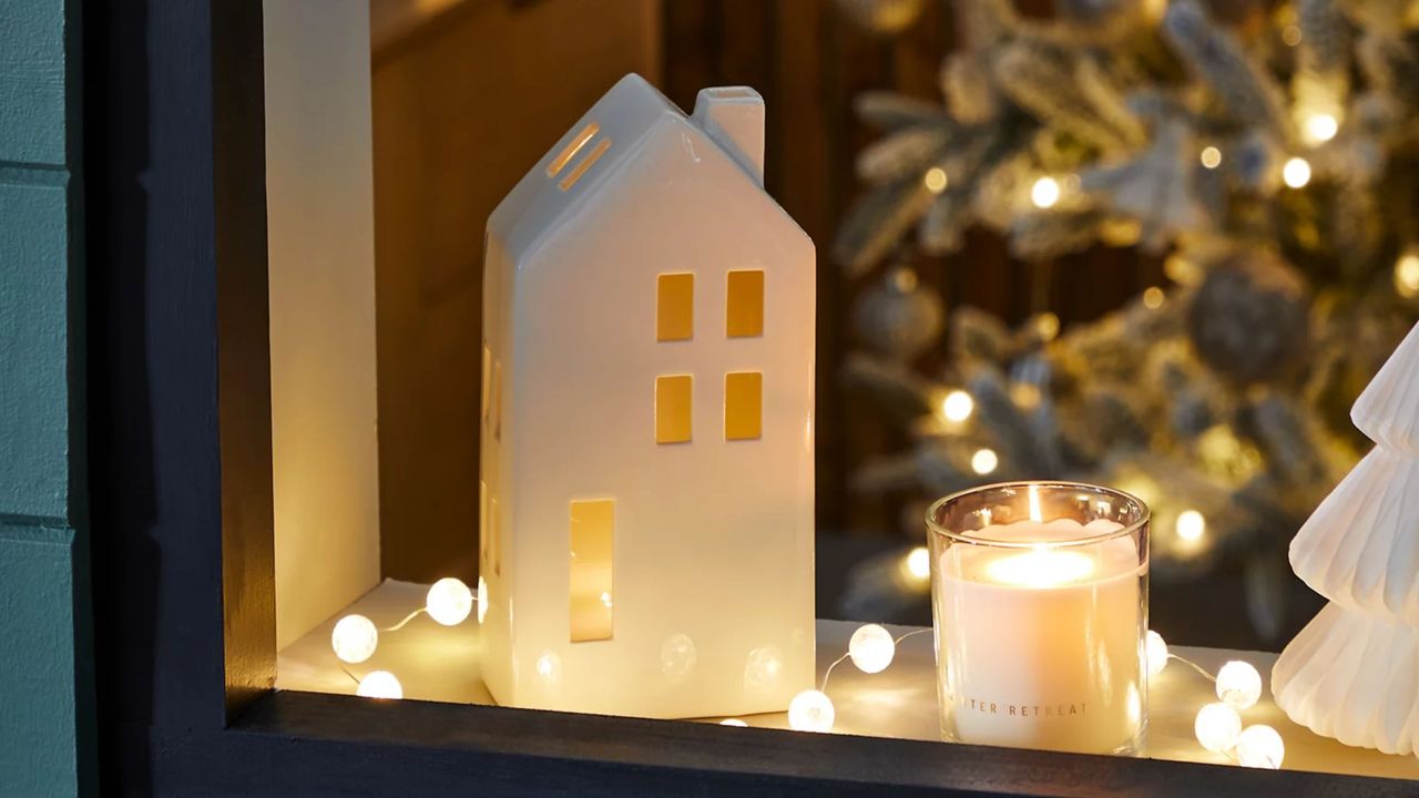 White Light Up House Decoration on a windowsill at Christmas